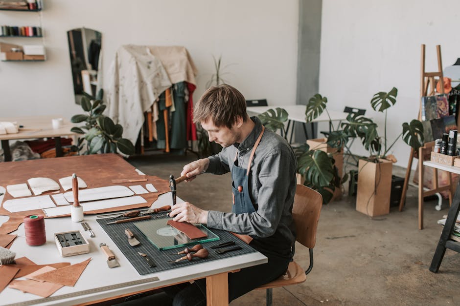 Leather craftsperson working at a table in a stylish workshop.