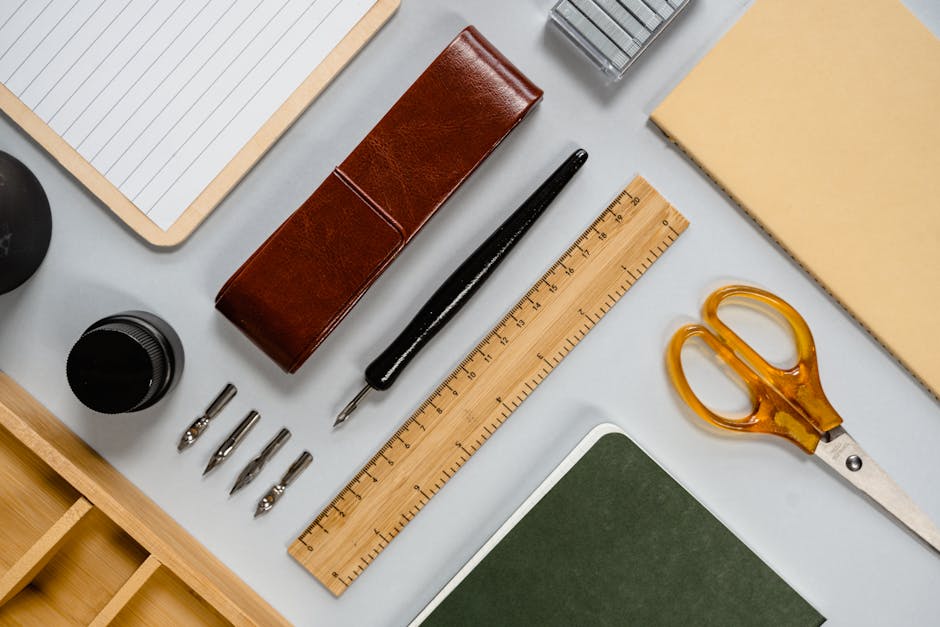 Flat lay of stylish desk stationery including pens, notebooks, and tools.
